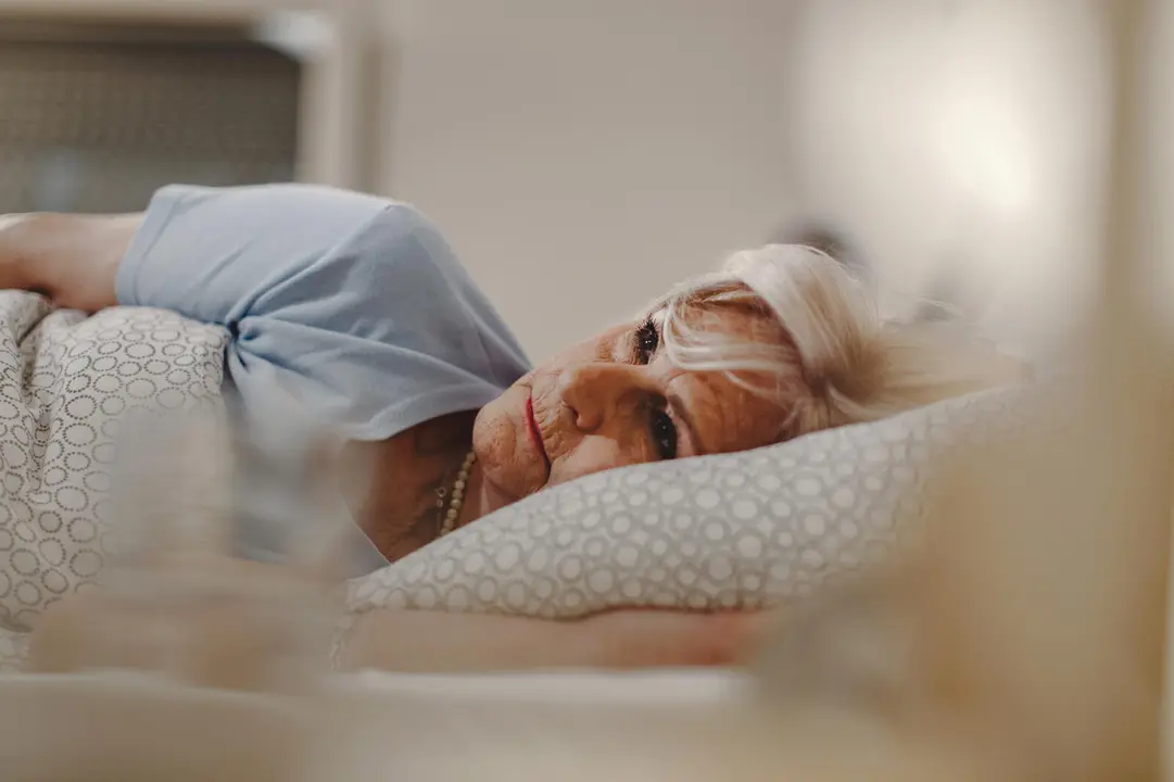 Pensive senior woman lying in the bed and thinking of something.