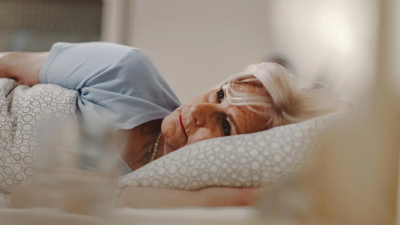 Pensive senior woman lying in the bed and thinking of something.