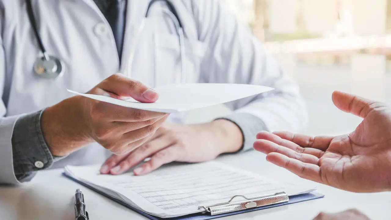 Doctor or physician writing diagnosis and giving a medical prescription to male Patient